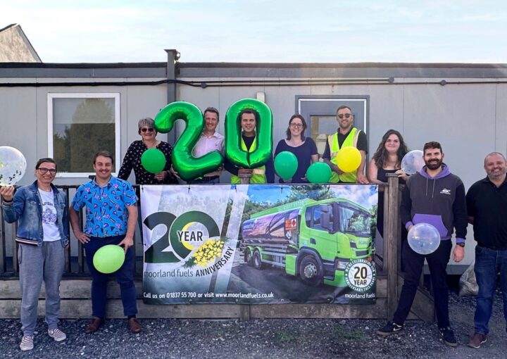 A group of colleagues stood outside the Moorland Fuels offices with a banner and balloons