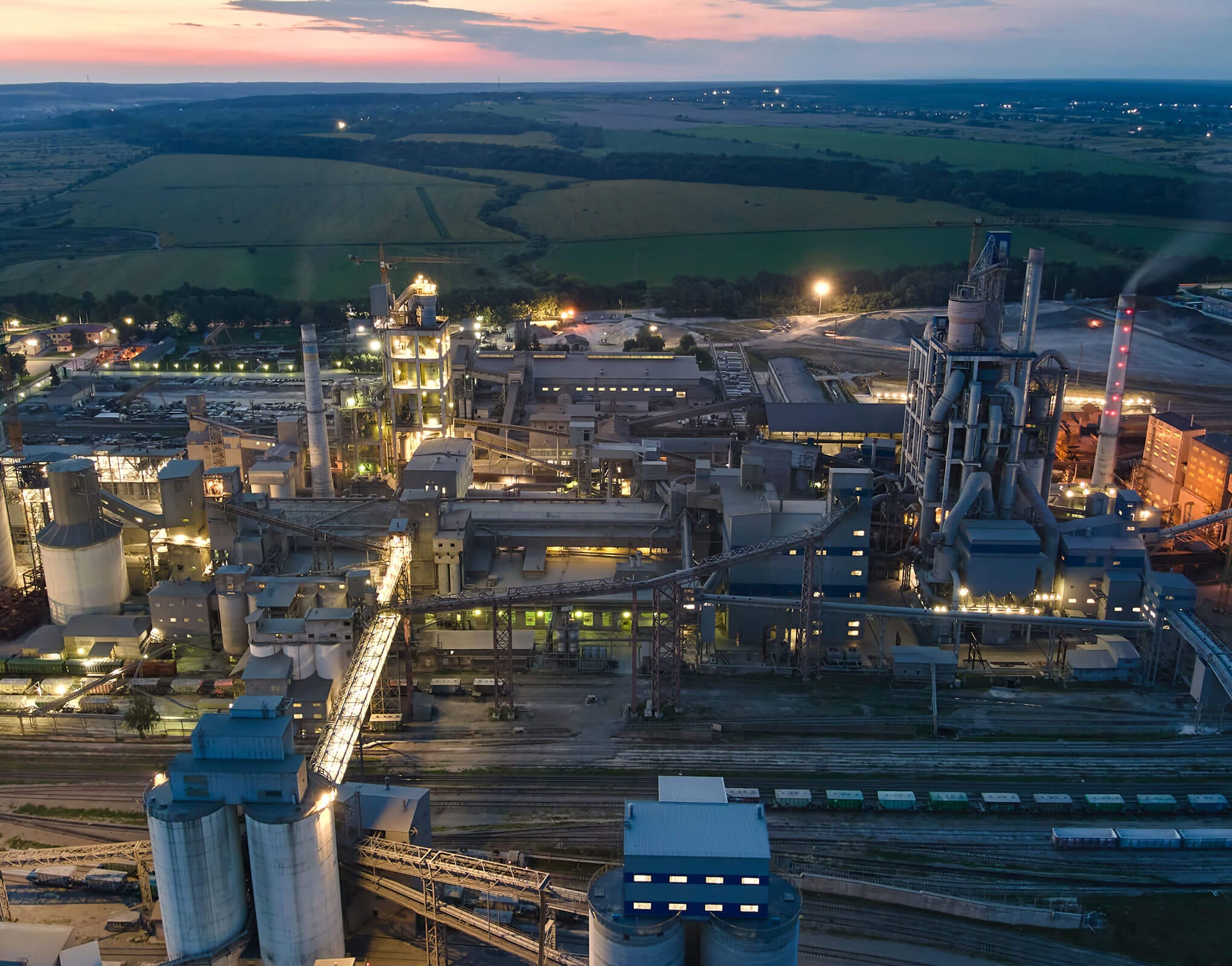 Aerial View of Industrial Plant at Dusk Aerial photograph of a large industrial facility during sunset, showing various structures and machinery.