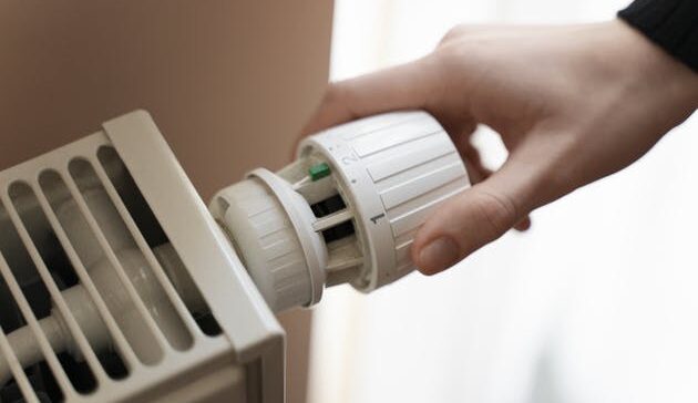 a person turning a themostat on a radiator